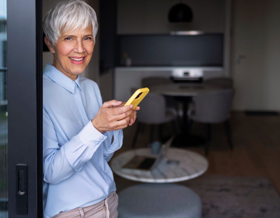 Dispositivos IoT que transformam o cuidado de saúde em casa mulher idosa mexendo no celular em casa