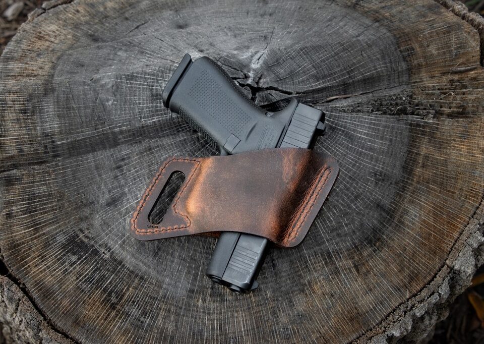a leather sheath with a gun on top of a piece of wood