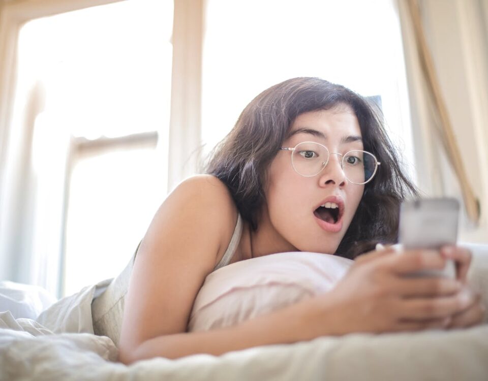 Woman Lying on Bed Holding Smartphone