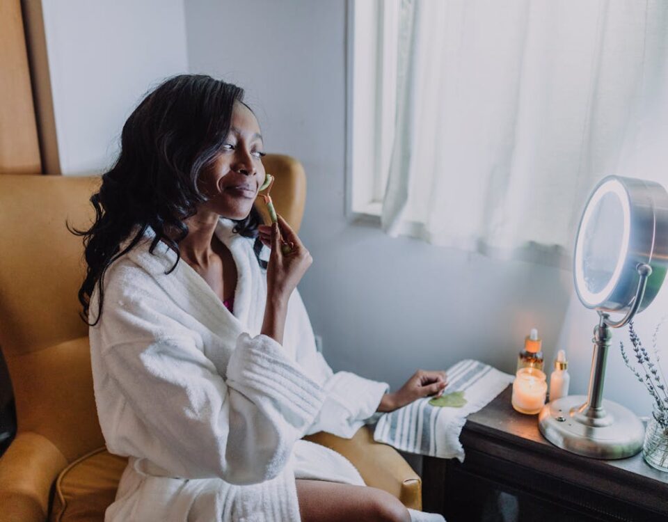 A Woman in White Bathrobe Massaging her face with a Jade Roller