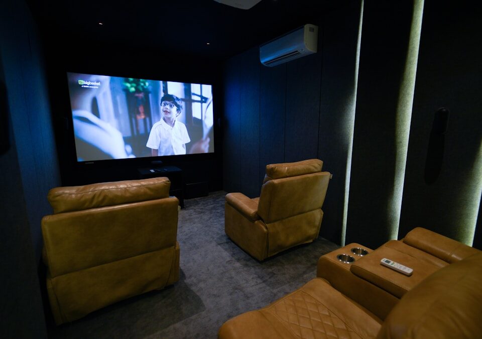 Como o som 3D transforma sua experiência de filmes A home theater with two recliners and a flat screen TV