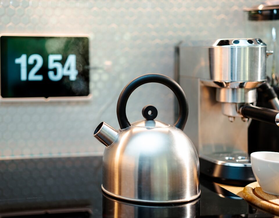 a tea kettle sitting on top of a counter next to a cup