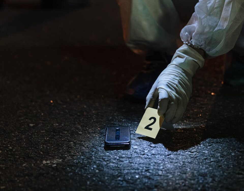 Forensic investigator examining evidence in a city street at night.