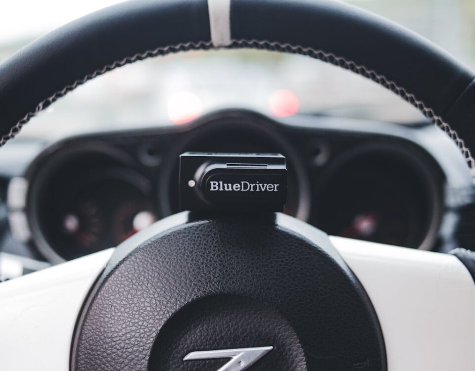 Gadgets que ajudam na redução do seguro do carro Close-up view of a BlueDriver device on a car steering wheel, highlighting automotive tech.