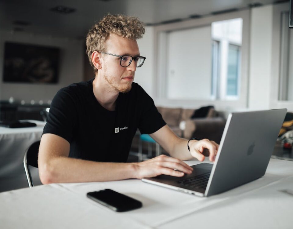 A focused young man working on a laptop in a modern office setting, highlighting productivity and technology.