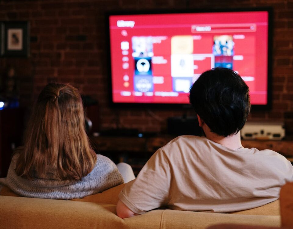 A couple enjoys streaming shows on a large TV in a cozy, brick-walled living room.