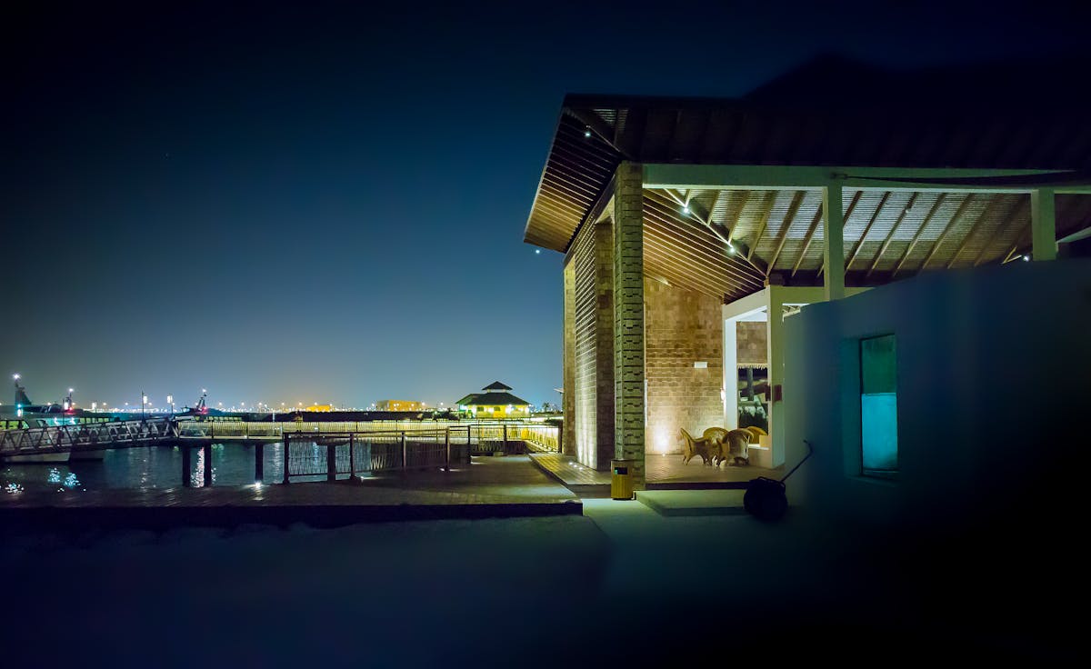 Gadgets que valorizam uma residência A modern waterfront house illuminated at night, featuring a serene cityscape and reflection on water.