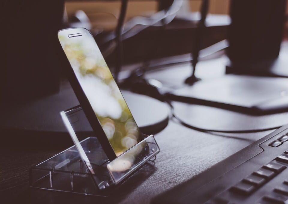 Workspace with smartphone on stand and keyboard, highlighting modern technology and productivity.