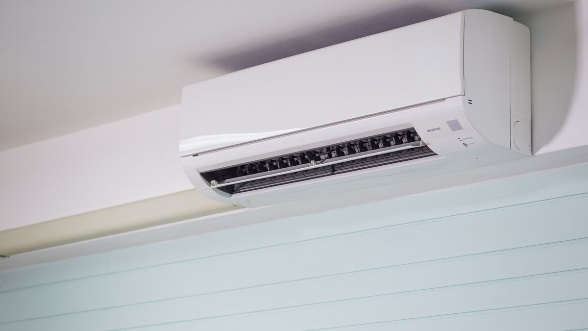 Aparelho de ar-condicionado split branco instalado no alto de uma parede