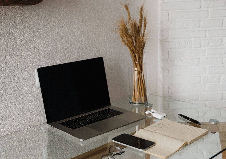 Notebook e dispositivos eletrônicos sobre uma mesa de trabalho.