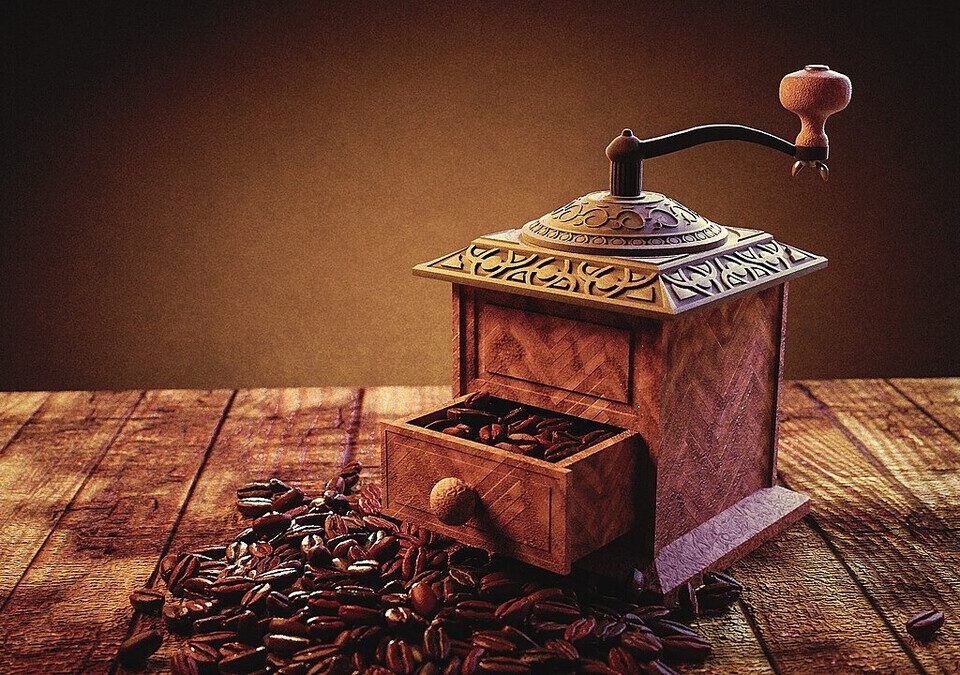 Moedor de café manual de madeira com grãos torrados sobre mesa
