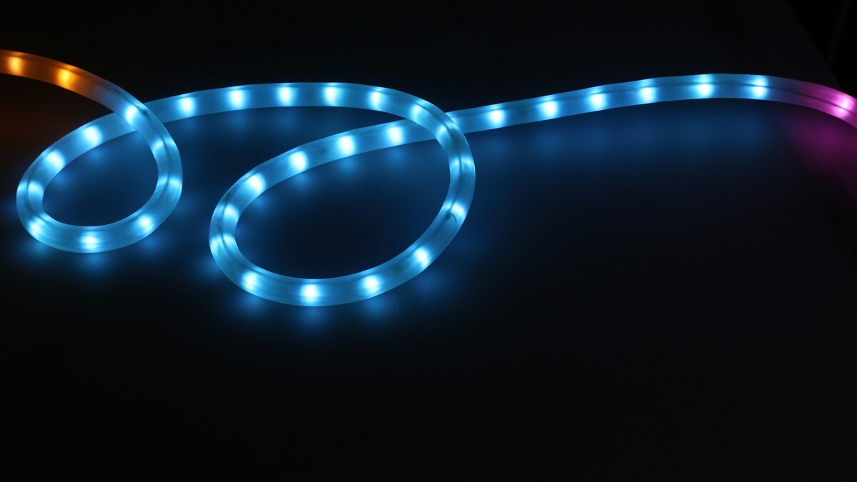 Mangueira de LED azul acesa formando curvas sobre superfície escura