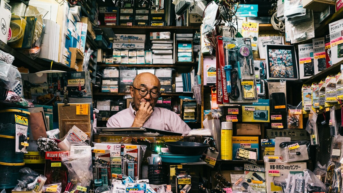 Homem ao lado de prateleiras com embalagens de acessórios eletrônicos
